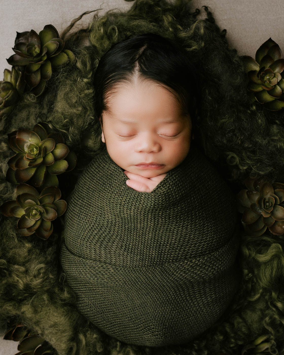 Close-Up Portrait Of A Newborn Baby Wrapped In Green Fabric