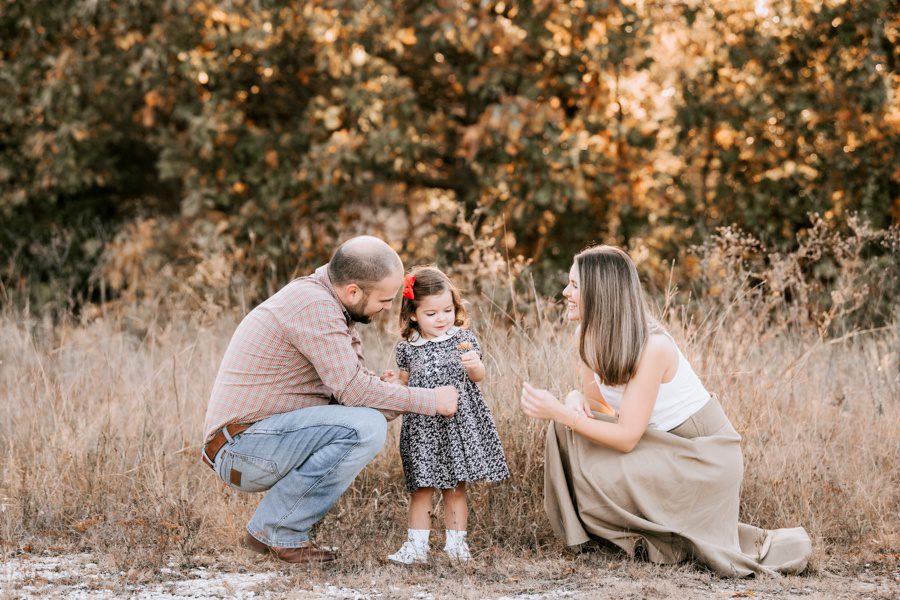 beautiful sunset photo little girl holding flower while parents are smiling