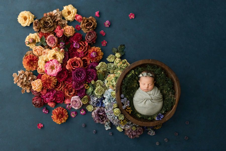 newborn in a blue setup with colorful floral