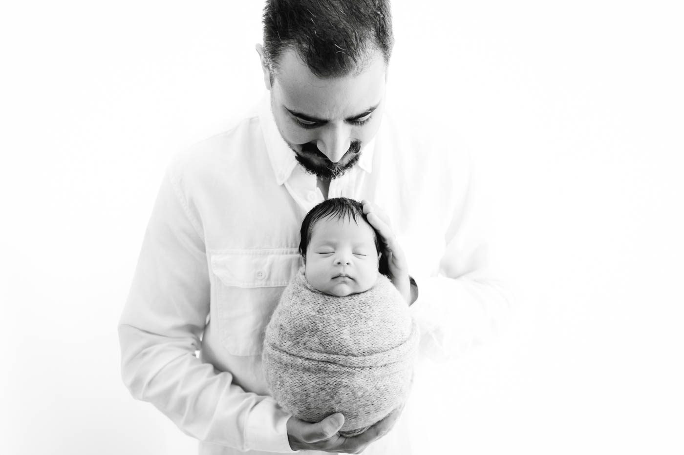 Father Holding A Wrapped Newborn During A Professional Newborn Photography Session