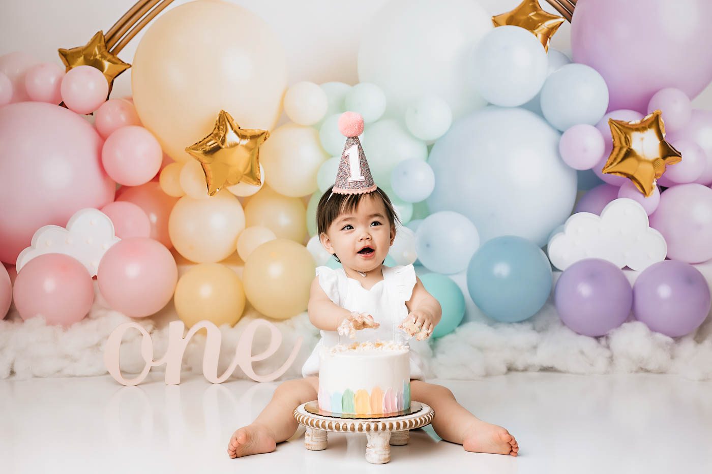 Baby Celebrating A First Birthday With A Pastel Balloon Cake Smash Setup