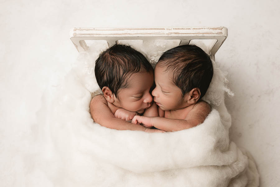 Twin Babies Sleeping Closely Together In A Soft Neutral Studio Setup With Delicate Textures.
