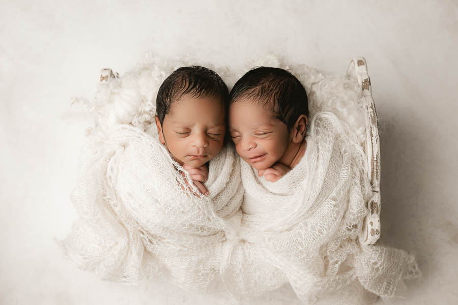 Twin Babies Peacefully Sleeping In Soft Neutral Wraps During A Calm Studio Baby Session.