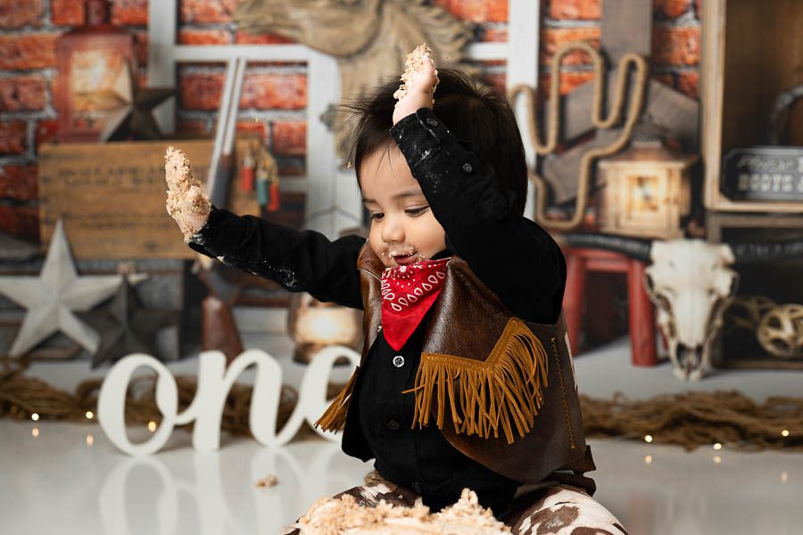 Ranch-Inspired First Birthday Session Ideas 5 Baby Smiling And Playing During A Western-Themed First Birthday Cake Smash Session.