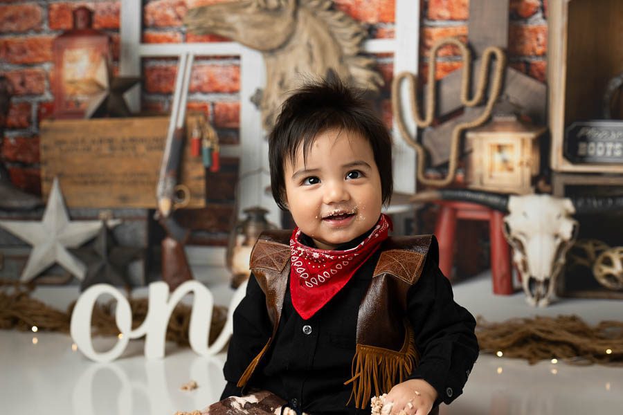Ranch-Inspired First Birthday Session Ideas 2 Baby Wearing Western-Inspired Outfit During A Rustic Cowboy-Themed First Birthday Portrait Session.