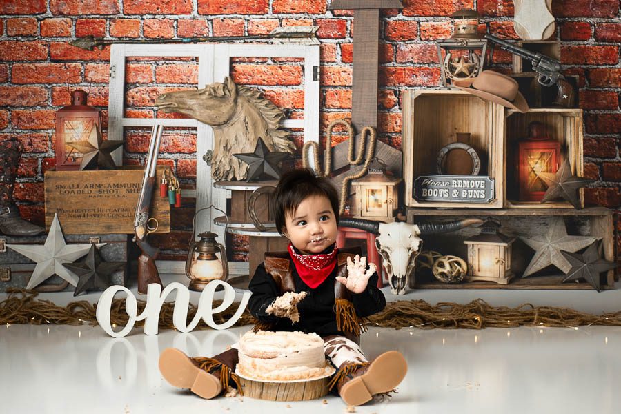 Ranch-Inspired First Birthday Session Ideas 1 Baby Sitting Beside Birthday Cake During A Western-Inspired First Birthday Session With Rustic Cowboy Décor.