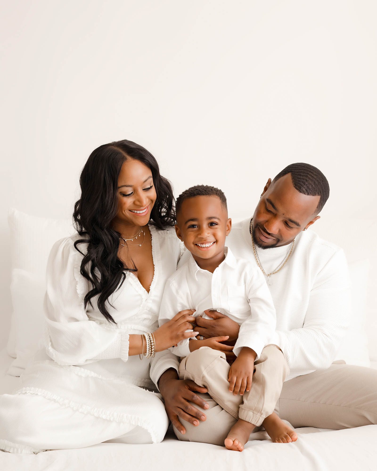 Smiling family of three in white outfits during a Dallas family photography studio session