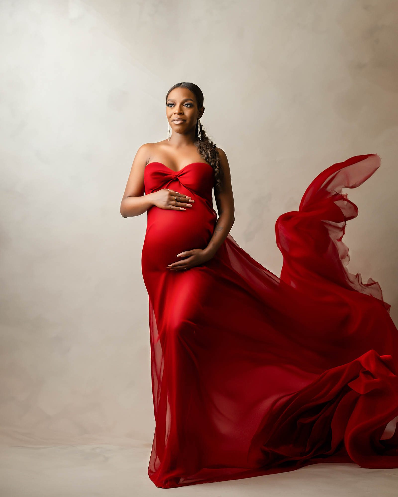 Pregnant mother in elegant flowing red gown during maternity photoshoot by Dallas maternity photographer