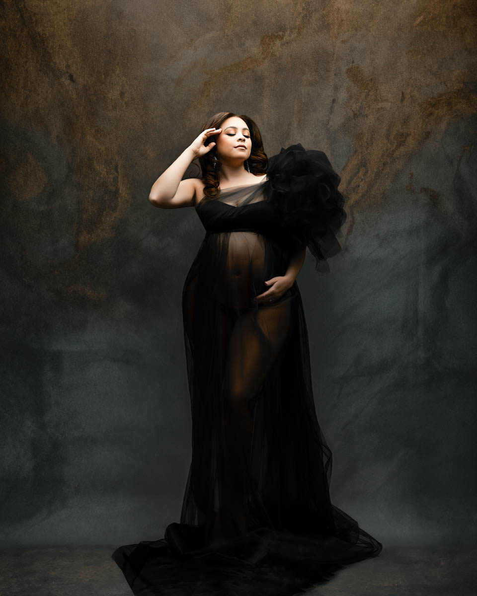 Fine art studio pregnancy portrait captured by a pregnancy photographer in Dallas featuring an expecting mother in an elegant black gown
