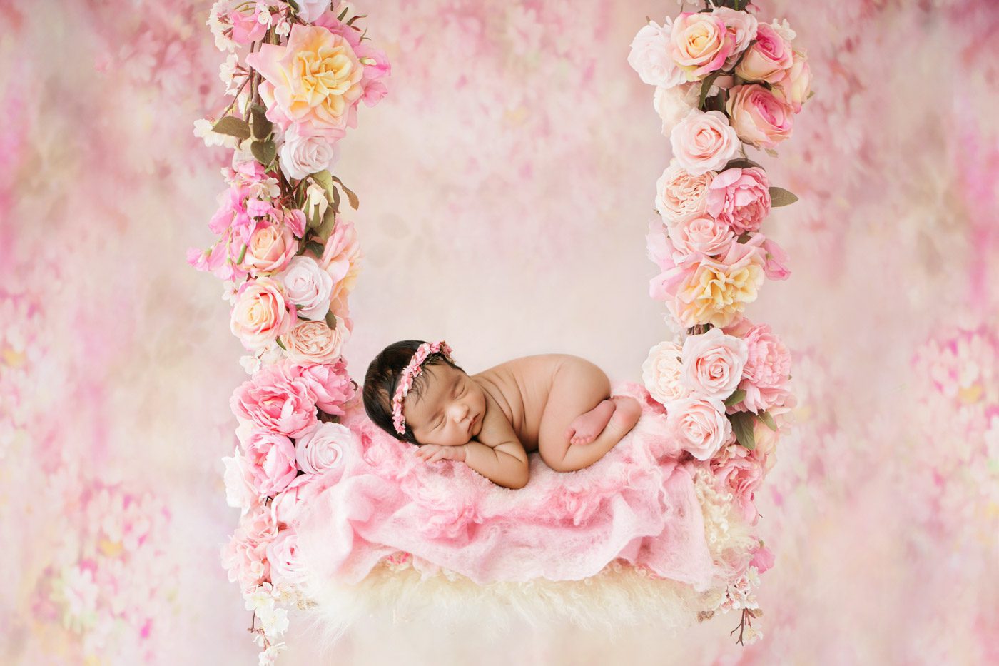 Artistic Newborn Photo With Pink Floral Setup And Soft Styling