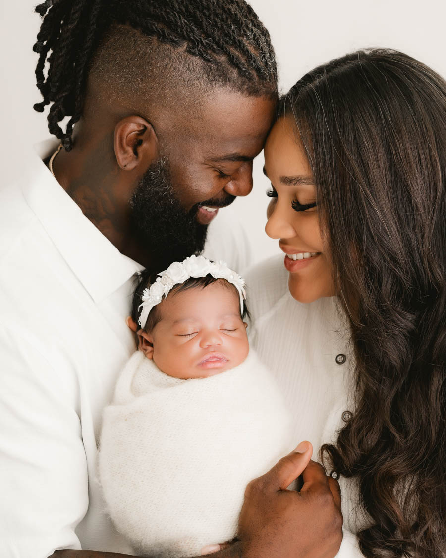 Parents Cuddling Their Newborn Baby During A Timeless Family Portrait Session