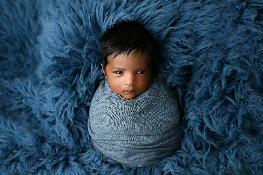 Sleeping Newborn Baby Wrapped In Blue Fabric On A Soft Textured Blanket