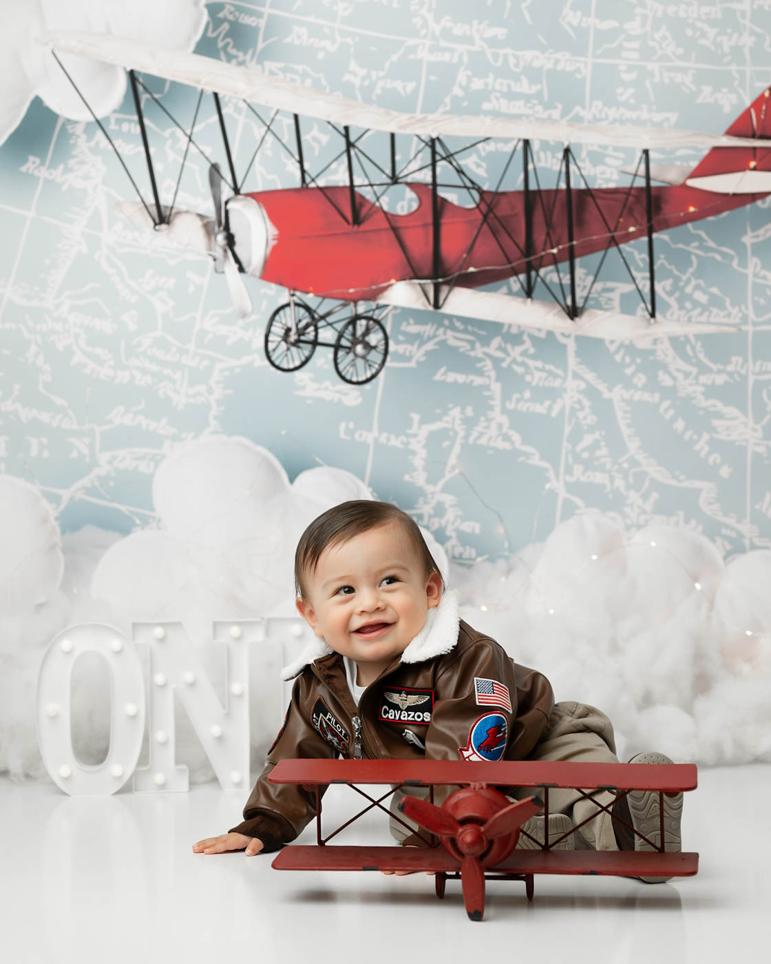 Baby Milestone Photos Featuring A One-Year-Old With An Airplane-Themed Backdrop In Dallas
