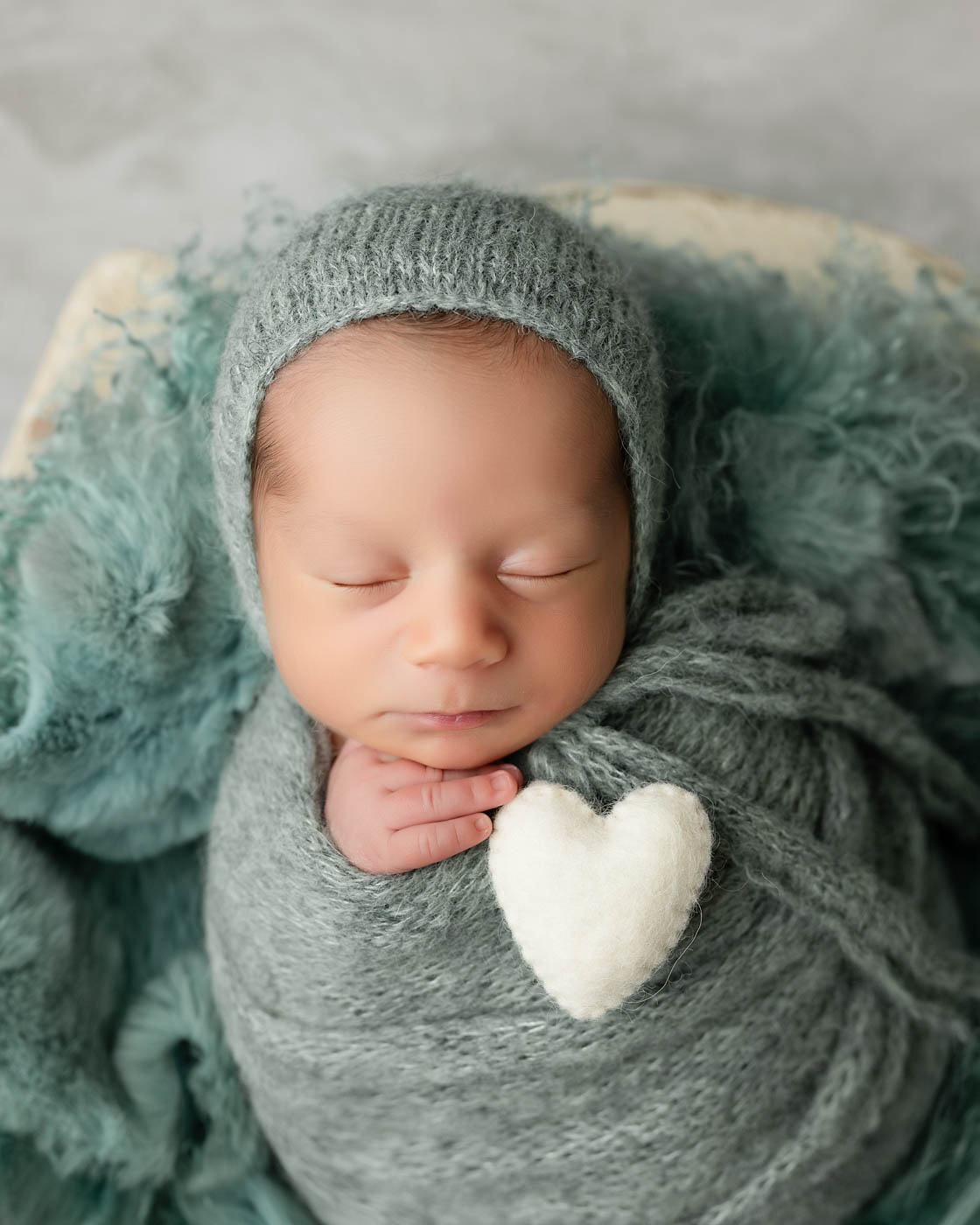 Artistic Newborn Portrait In Dallas Featuring A Sleeping Baby With A Handcrafted Heart Accent And Soft Knitted Wrap.