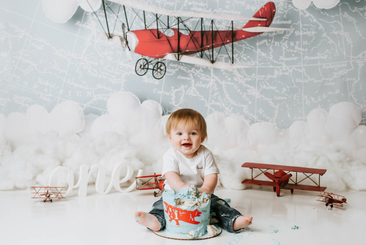 Baby boy celebrating his first birthday with an airplane-themed cake smash photography session in Dallas, featured alongside a five-star client review.