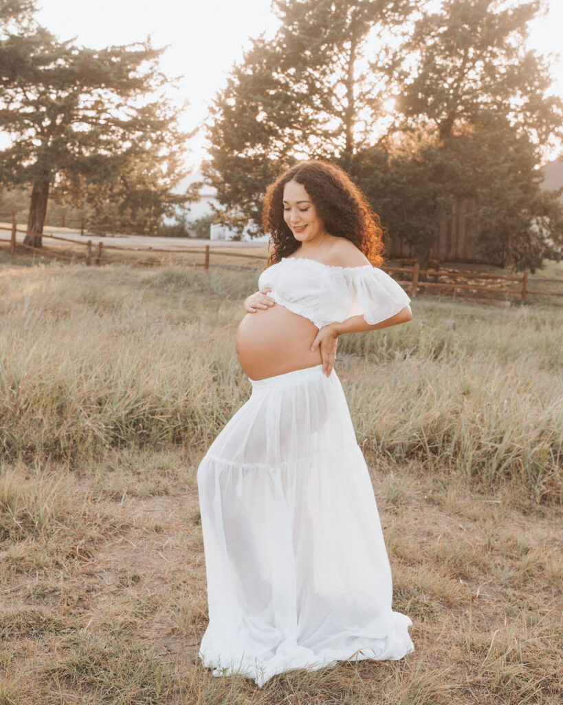 Outdoor Pregnancy Portrait By A Dallas Maternity Photographer Featuring An Expecting Mother In A Flowing White Dress