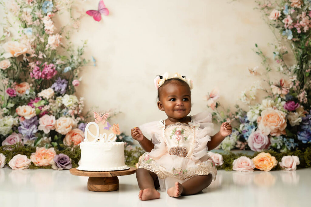 First Birthday Cake Smash Session By A Dallas Cake Smash Photographer Featuring A Baby Girl With A Floral Cake Smash Setup