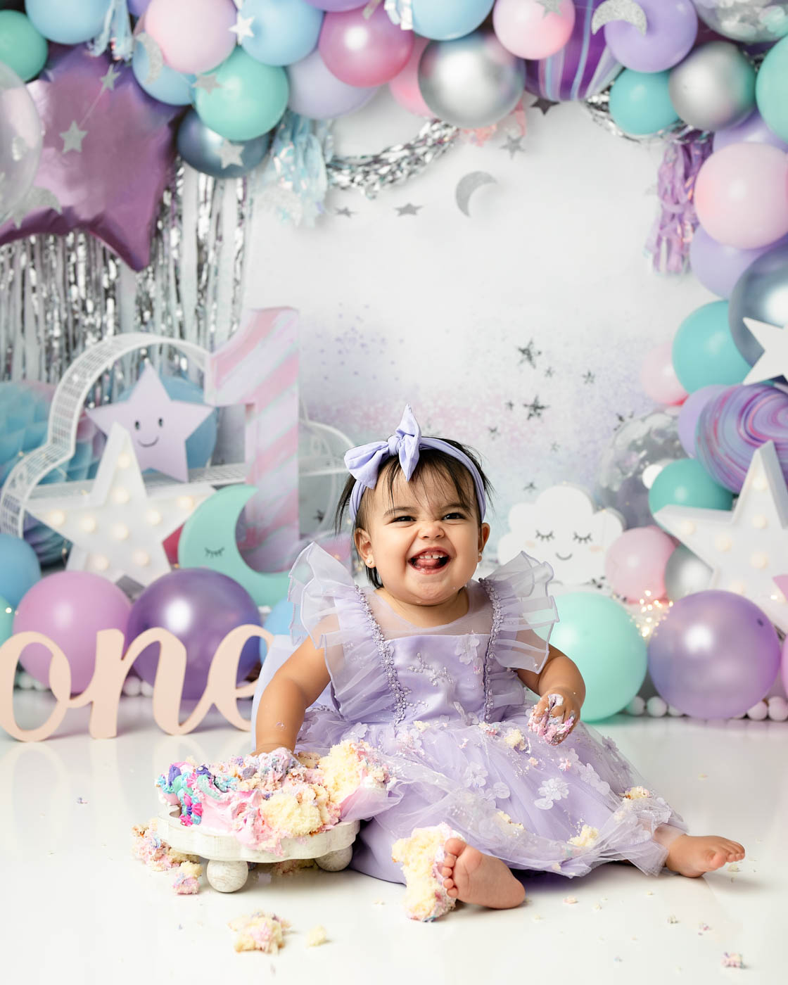 One-year-old girl smiling during a pastel cake smash session at Lily Hayes Photography, a Dallas cake smash photographer specializing in custom first birthday portraits.