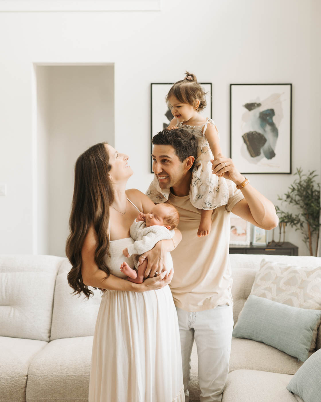 Family of four enjoying an in-home lifestyle newborn photography session in Dallas with parents, toddler, and their newborn baby.