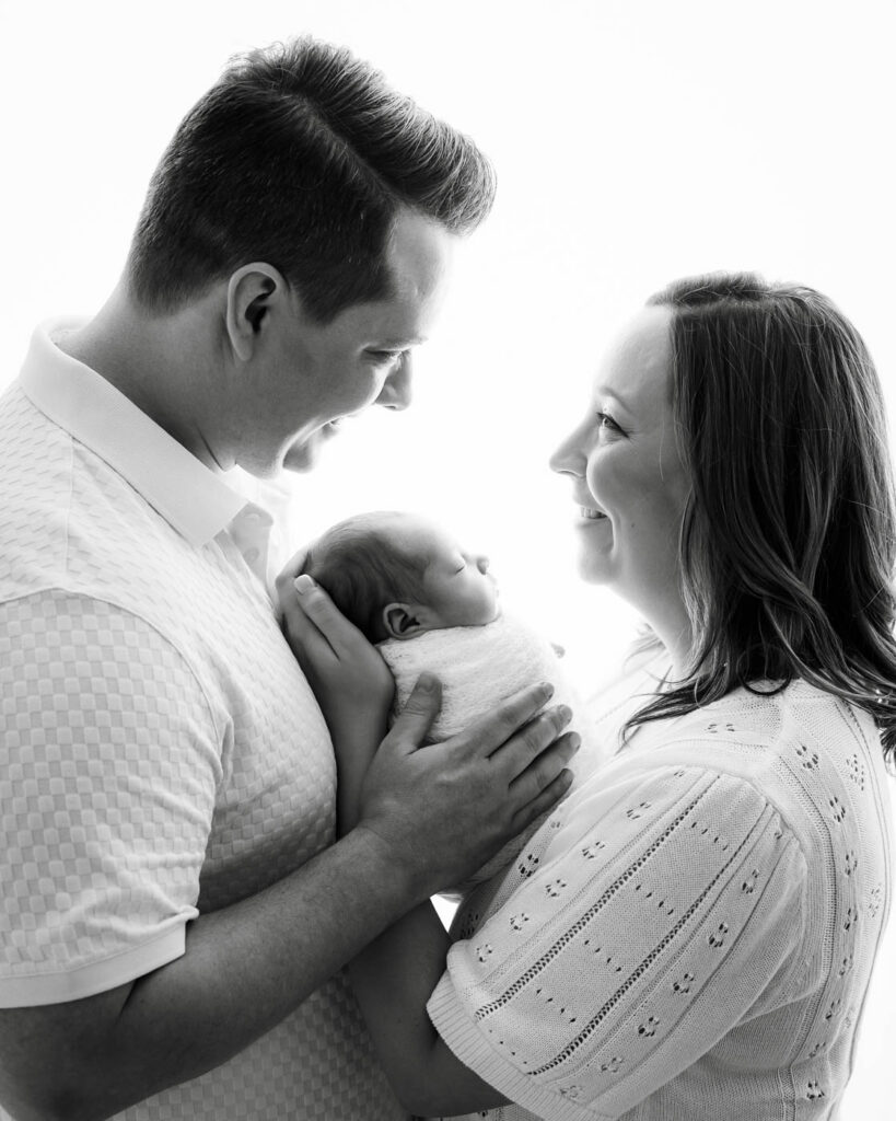 Dallas Baby Photographer Creating A Relaxed Portrait Of Parents Holding Their Newborn Baby Together