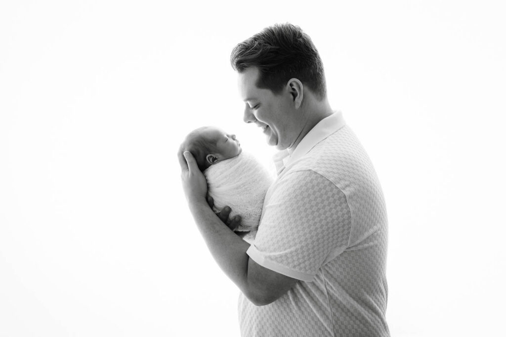 Father Holding His Newborn Baby During A Session At A Newborn Photography Studio In The Dallas Area