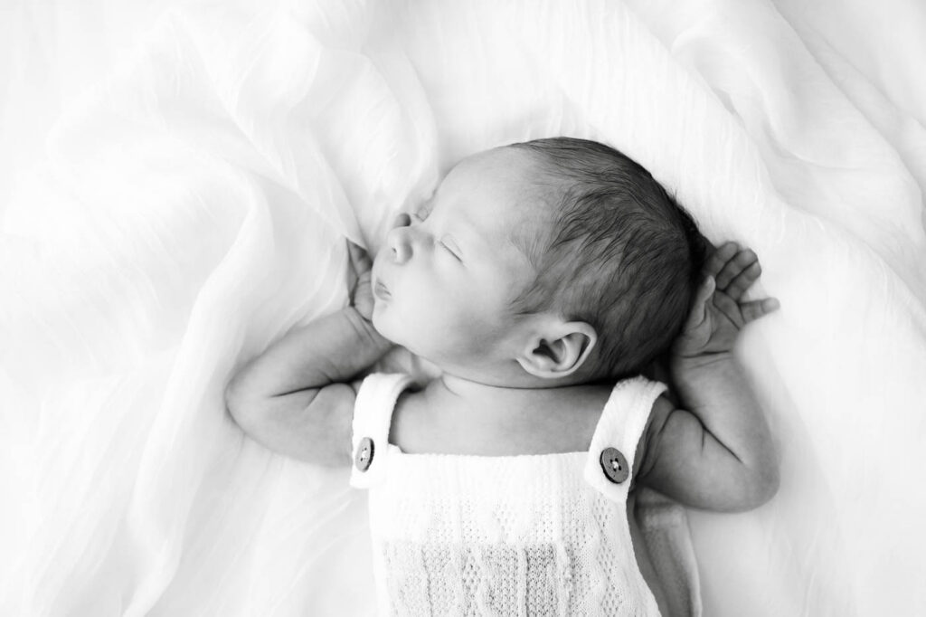 Professional Newborn Photographer In Dallas Creating A Simple Portrait Of A Sleeping Baby On A White Studio Bed