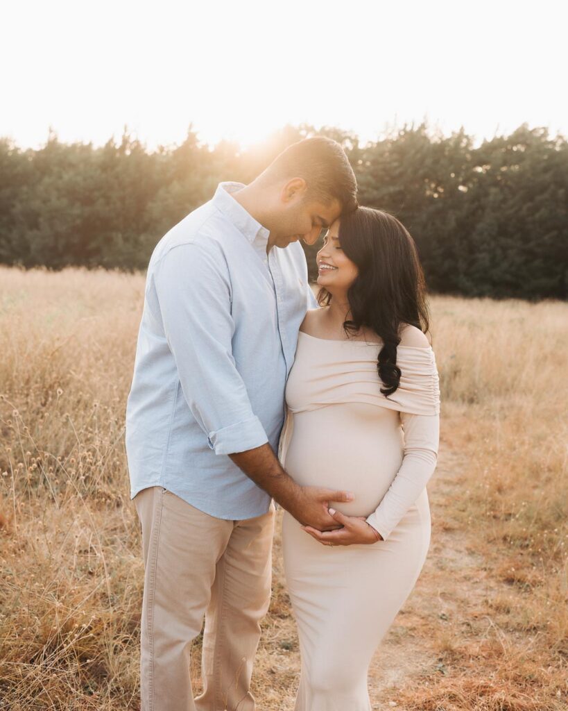 Expecting Couple Posed Together During A Dallas Maternity Photoshoot With Both Hands Gently Placed Near The Baby Bump.