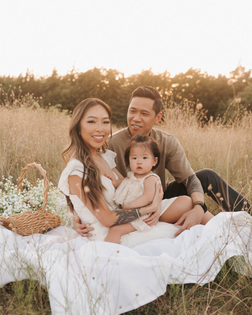 What If My Child Won’t Cooperate During Family Photos? 5 Parents Sit Together With Their Toddler On A Picnic Blanket During A Relaxed Family Photography Session In Dallas.