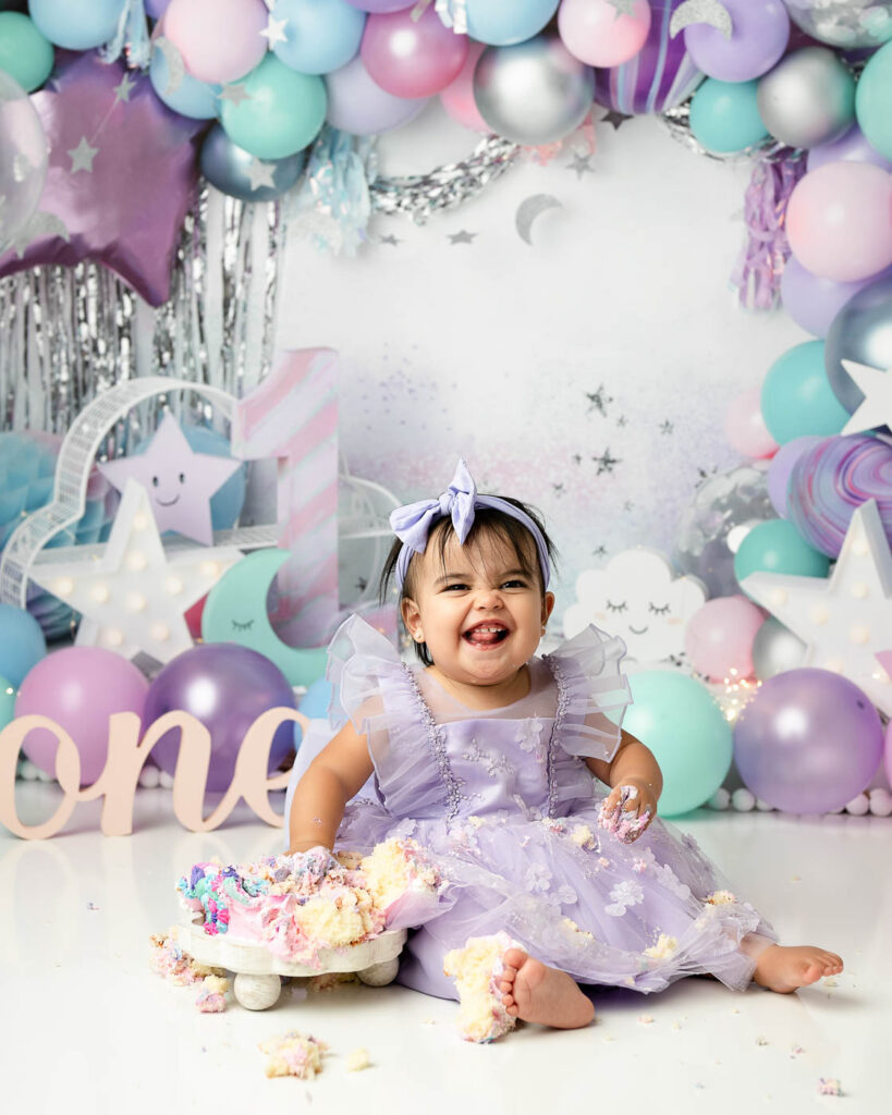 Baby Girl Smiling During A Pastel Winter Cake Smash Session In Dallas