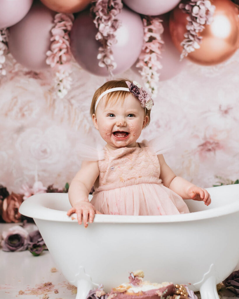 Baby Girl Smiling During A Splash Bath After A Dallas Cake Smash Session