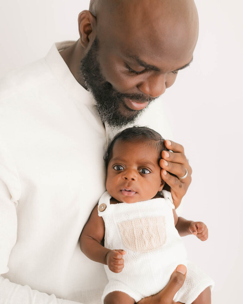 Father Holding His Newborn During A Dallas Newborn Photography Studio Session