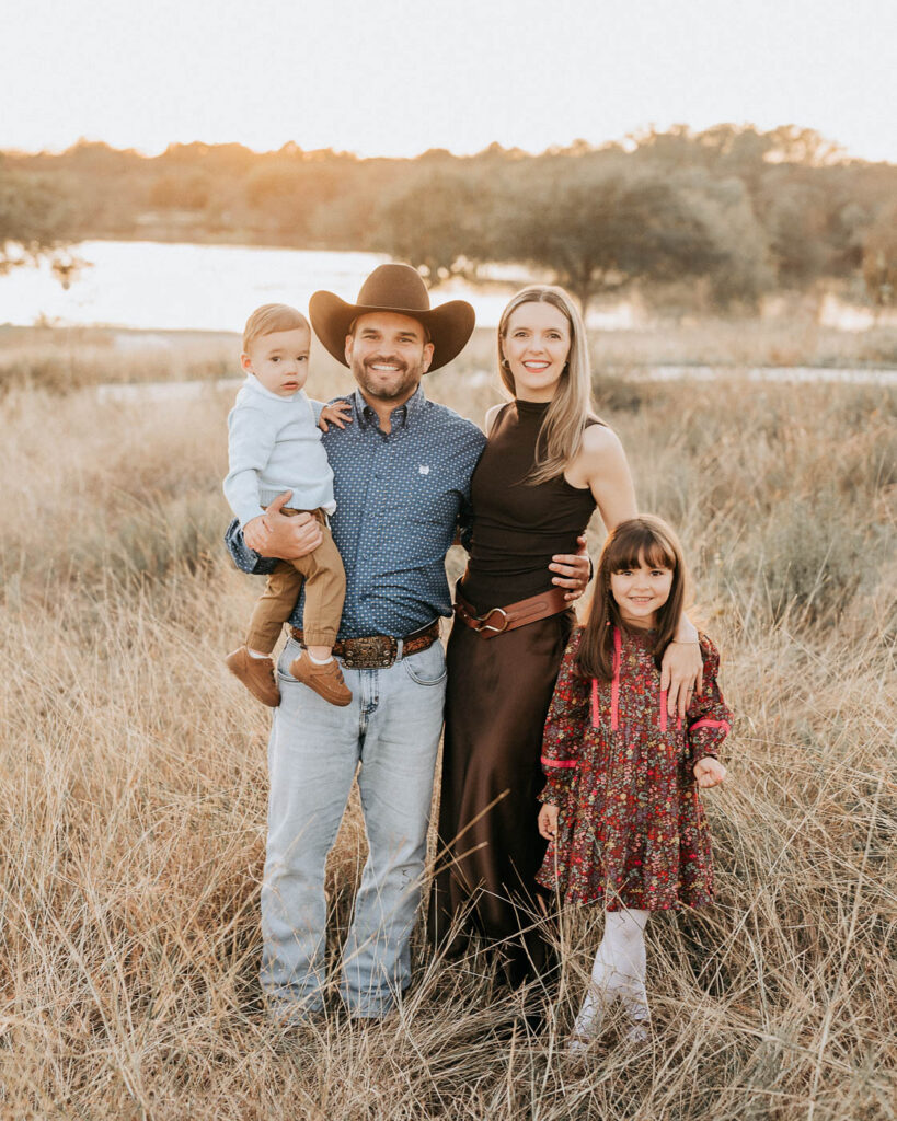 How A Dallas Family Photographer Works With Young Kids Who Don’t Want To Sit Still 3 Parents And Their Young Children Standing Together During An Outdoor Family Session In Dallas.