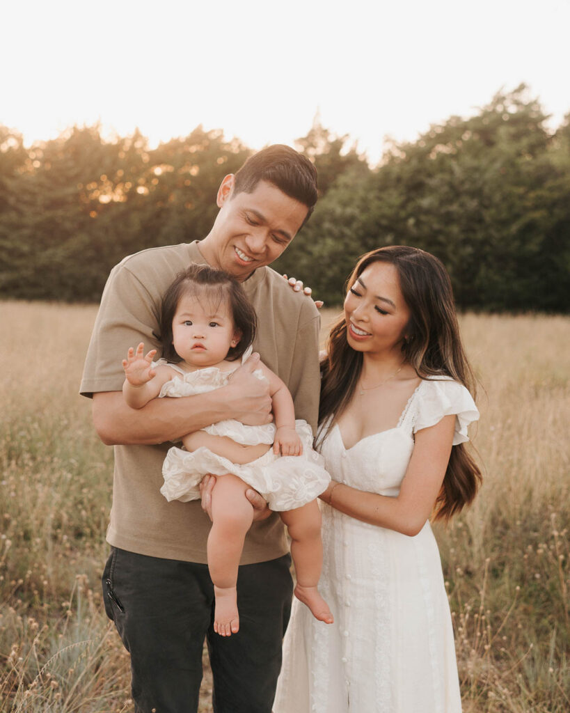 How A Dallas Family Photographer Works With Young Kids Who Don’t Want To Sit Still 7 Parents Holding Their Young Daughter During An Outdoor Dallas Family Photography Session.