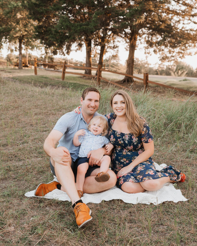 Maternity Photos With A Toddler: What Actually Works 5 Expecting Parents Sitting With Their Toddler During An Outdoor Dallas Maternity Photography Session.