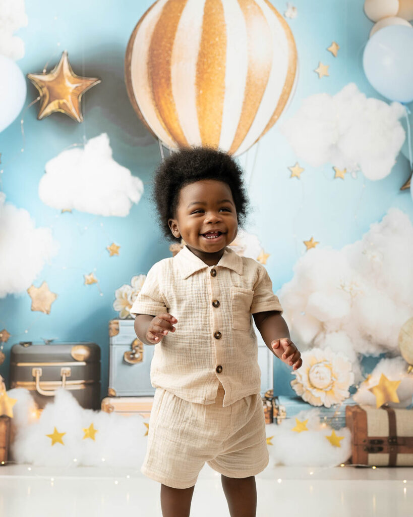 Smiling One-Year-Old Standing During A Dallas Cake Smash Photography Session.
