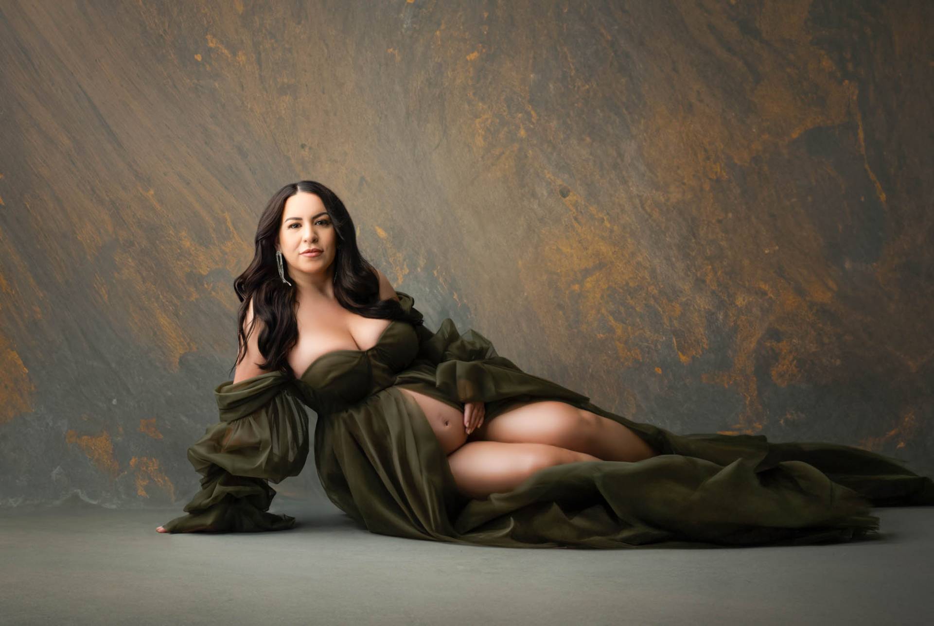 Dallas maternity photographer Lily Hayes Photography captures a luxury studio maternity portrait featuring an expecting mother in an elegant olive green gown against a fine-art textured backdrop.